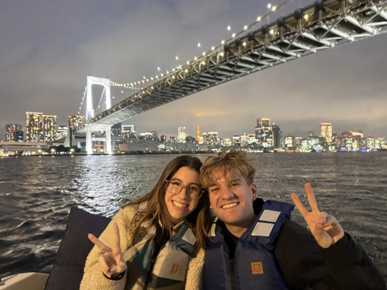 German couple on Tokyo Bay private cruise with Rainbow Bridge and Tokyo Tower illuminated at night